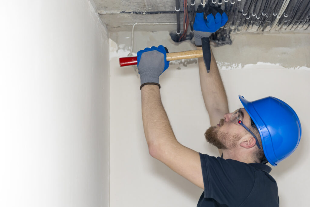 Electrician installing laying electrical cables on the ceiling inside the house.